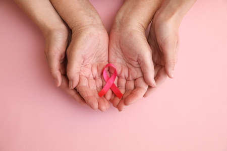 Senior woman and her adult daughter holding pink ribbon on color background, top view. Breast cancer awarenessの写真素材