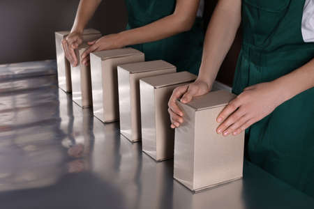 People packing cardboard boxes at production line, closeupの写真素材