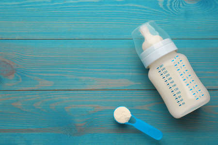 Feeding bottle with infant formula and powder on light blue wooden table, flat lay. Space for textの写真素材