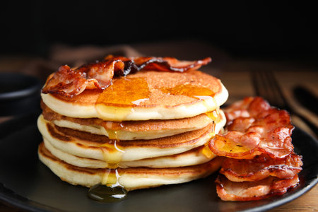 Delicious pancakes with maple syrup and fried bacon on plate, closeupの写真素材