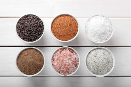 Different kinds of salt on white wooden table, flat layの写真素材