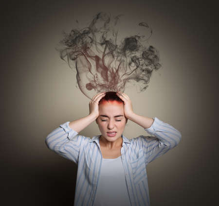 Young woman having headache on beige background. Illustration of smoke representing severe painの写真素材