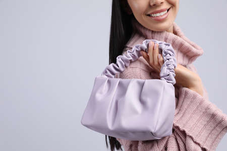 Fashionable young woman with stylish bag on light background, closeup. Space for textの写真素材