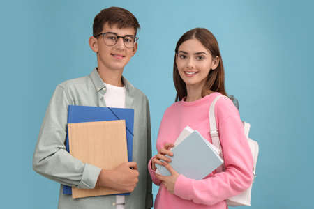 Teenage students with stationery and backpack on turquoise backgroundの写真素材