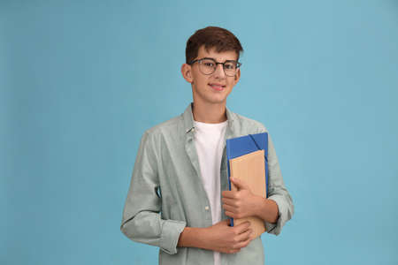 Teenage student with glasses and stationery on turquoise backgroundの写真素材