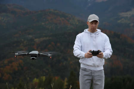 Young man operating modern drone with remote control in mountainsの写真素材