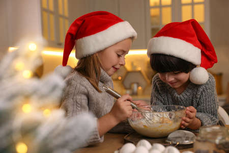 Cute little children making dough for Christmas cookies in kitchenの写真素材