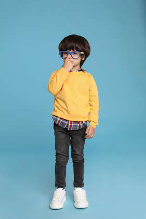 Cute little boy with funny glasses on light blue backgroundの写真素材