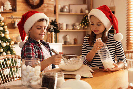 Cute little children making dough for Christmas cookies at homeの写真素材