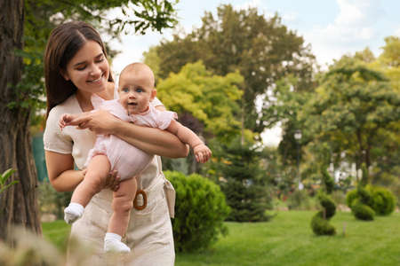 Happy mother with adorable baby walking in park on sunny day, space for textの写真素材