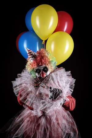 Terrifying clown with air balloons on black background. Halloween party costumeの写真素材