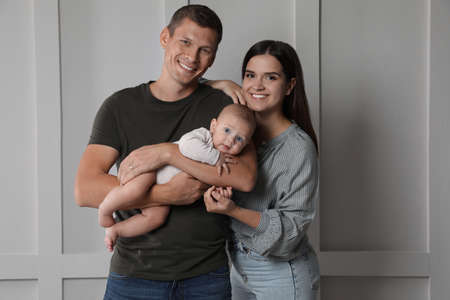 Happy family. Couple with their cute baby near light wallの写真素材