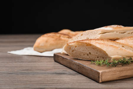 Cut tasty baguette with thyme on wooden table. Space for textの写真素材