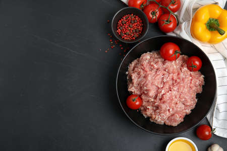 Raw chicken minced meat and ingredients on black table, flat lay. Space for textの写真素材