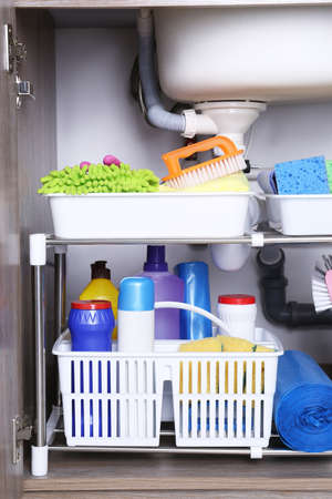 Open under sink cabinet with different cleaning supplies in kitchenの写真素材