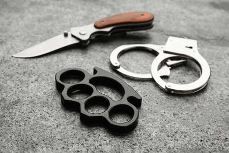 Brass knuckles, handcuffs and knife on gray backgroundの写真素材