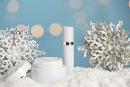 Jar of hand cream and lip balm near decorative snowflakes on snow against blurred lights. Winter skin care cosmeticsの写真素材