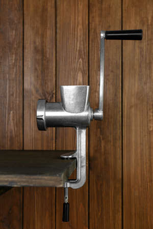 Metal manual meat grinder on table against wooden backgroundの写真素材