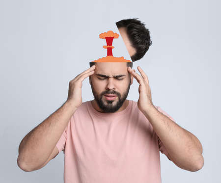 Young man having headache on light background. Illustration of atomic explosion representing severe...