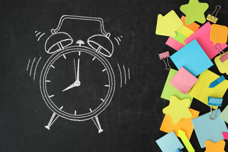 Different stationery and drawn alarm clock on blackboard surface, flat lay. Time to schoolの写真素材