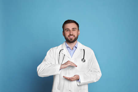 Young doctor holding something on light blue backgroundの写真素材