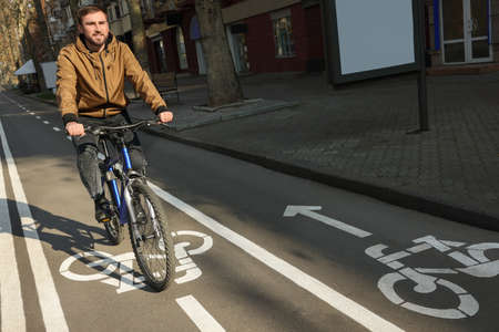 Happy handsome man riding bicycle on lane in cityの写真素材