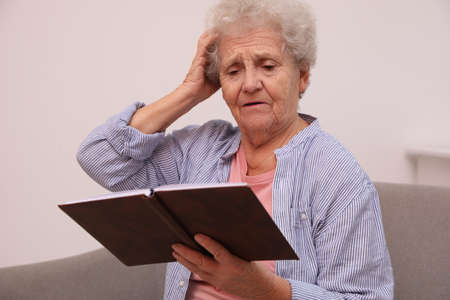 Senior woman with notebook at home. Age-related memory impairmentの写真素材