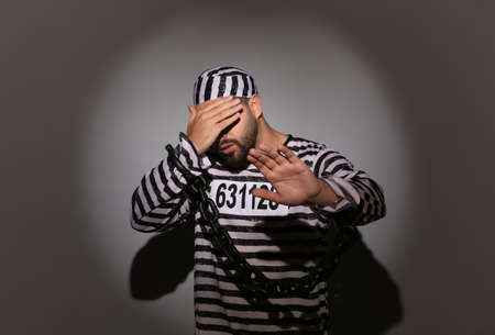 Prisoner in special uniform with chained hands on gray backgroundの写真素材