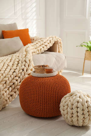 Tray with cup of tea and cookies on stylish comfortable pouf in room. Home designの写真素材