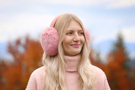 Young beautiful woman wearing warm earmuffs outdoors