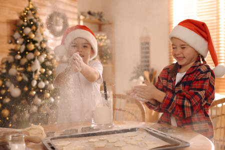 Cute little children having fun while making delicious Christmas cookies at homeの写真素材