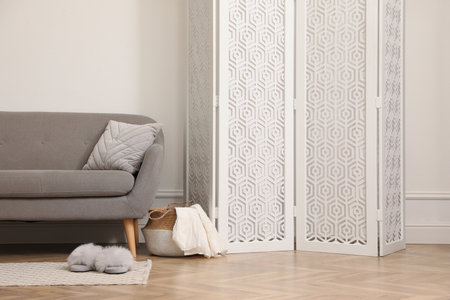 Stylish room with folding screen and sofa near white wall. Interior designの写真素材