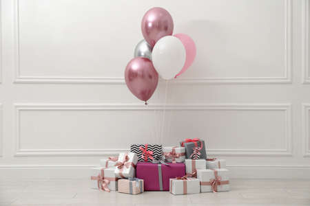 Many gift boxes and balloons near white wallの写真素材