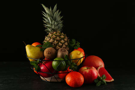 Fresh ripe fruits and metal bowl on black tableの写真素材
