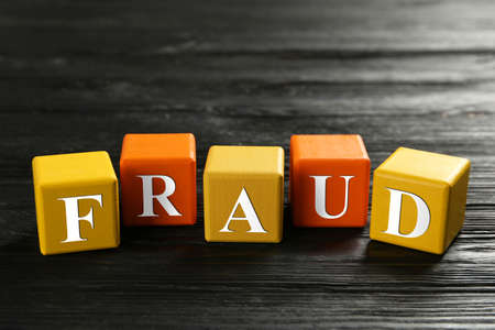 Cubes with word Fraud on black wooden backgroundの写真素材