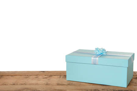Light blue gift box with bow on wooden table against white background, space for textの写真素材