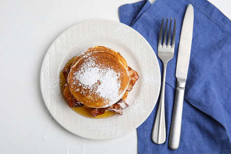 Delicious pancakes with maple syrup, sugar powder and fried bacon on white table, flat layの写真素材
