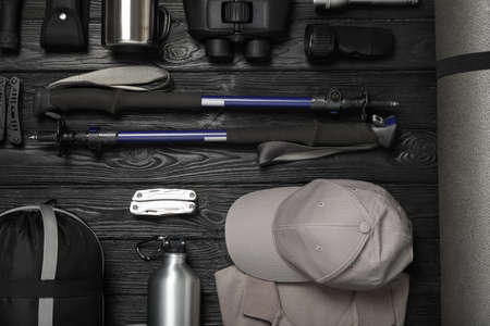 Flat lay composition with trekking poles and other hiking equipment on black wooden backgroundの写真素材
