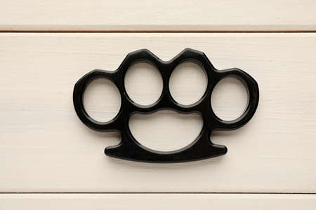 Black brass knuckles on white wooden background, top viewの写真素材