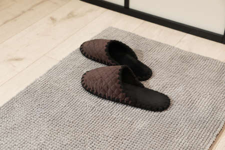 New gray bath mat with soft slippers on floor indoorsの写真素材