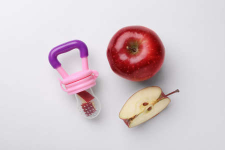 Nibbler with fresh apple on white background, flat lay. Baby feederの写真素材