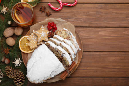 Traditional Christmas Stollen with icing sugar on wooden table, flat lay. Space for text