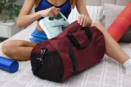 Woman packing sports stuff for training into bag at home, closeupの写真素材