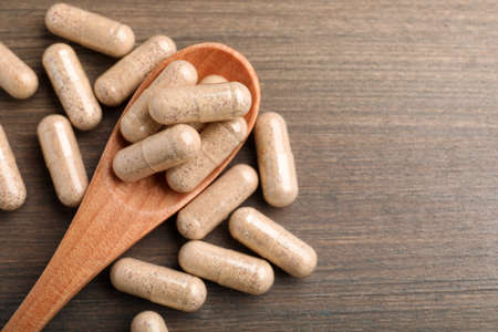 Gelatin capsules and spoon on wooden table, flat lay. Space for textの写真素材