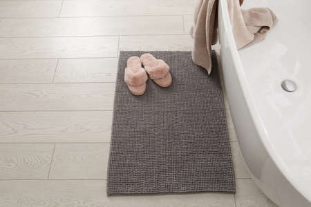 Soft gray bath mat and slippers on floor in bathroomの写真素材