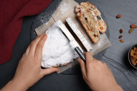 Woman cutting traditional Christmas Stollen at black table, top viewの写真素材