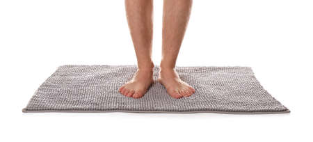 Man standing on soft gray bath mat against white background, closeupの写真素材