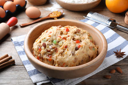 Raw dough with candied fruits and nuts for Stollen in bowl on wooden table. Baking traditional German Christmas breadの写真素材