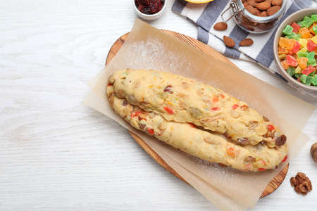 Unbaked Stollen with candied fruits and raisins on white wooden table, flat lay. Space for textの写真素材
