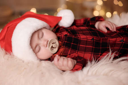 Cute baby in Santa hat sleeping on soft faux fur indoors. Christmas seasonの写真素材